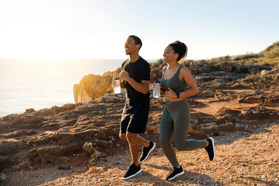 an active couple run near a waterfront cliff