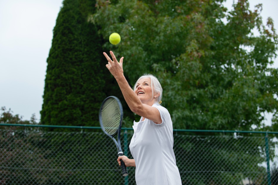 a woman throws up a tennis ball about to serve