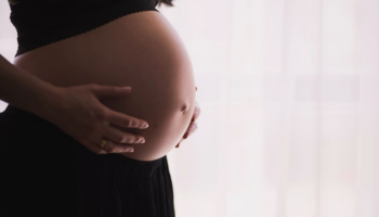 A pregnant woman gently holding her belly.