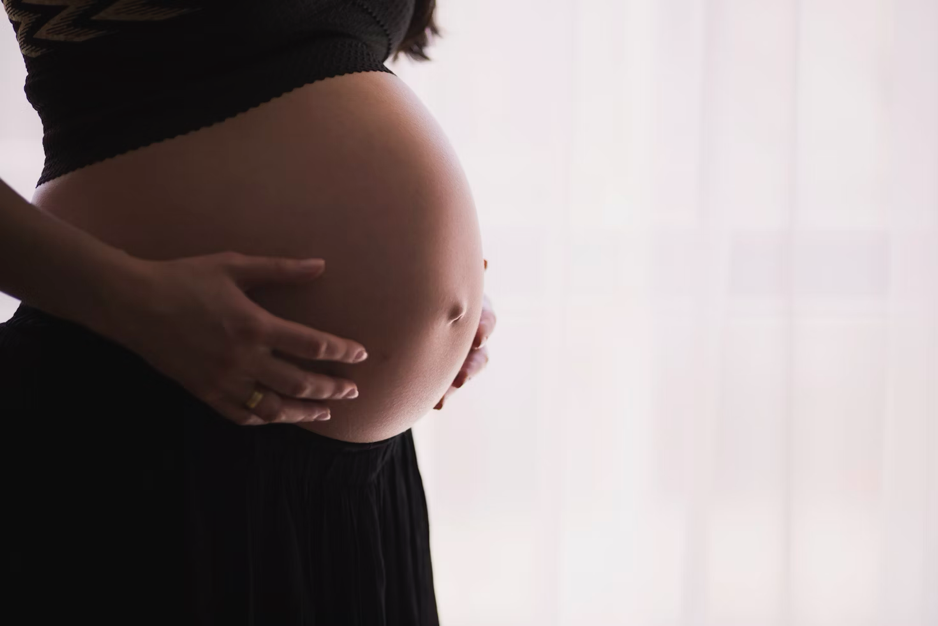 A pregnant woman gently holding her belly.