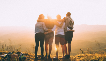 A group of young adults enjoying the sunset while hiking.