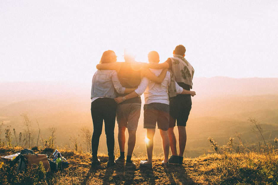 A group of young adults enjoying the sunset while hiking.