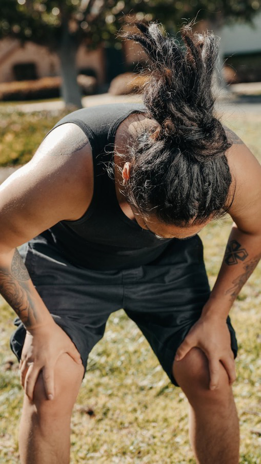 A person experiencing knee pain holding their knees.