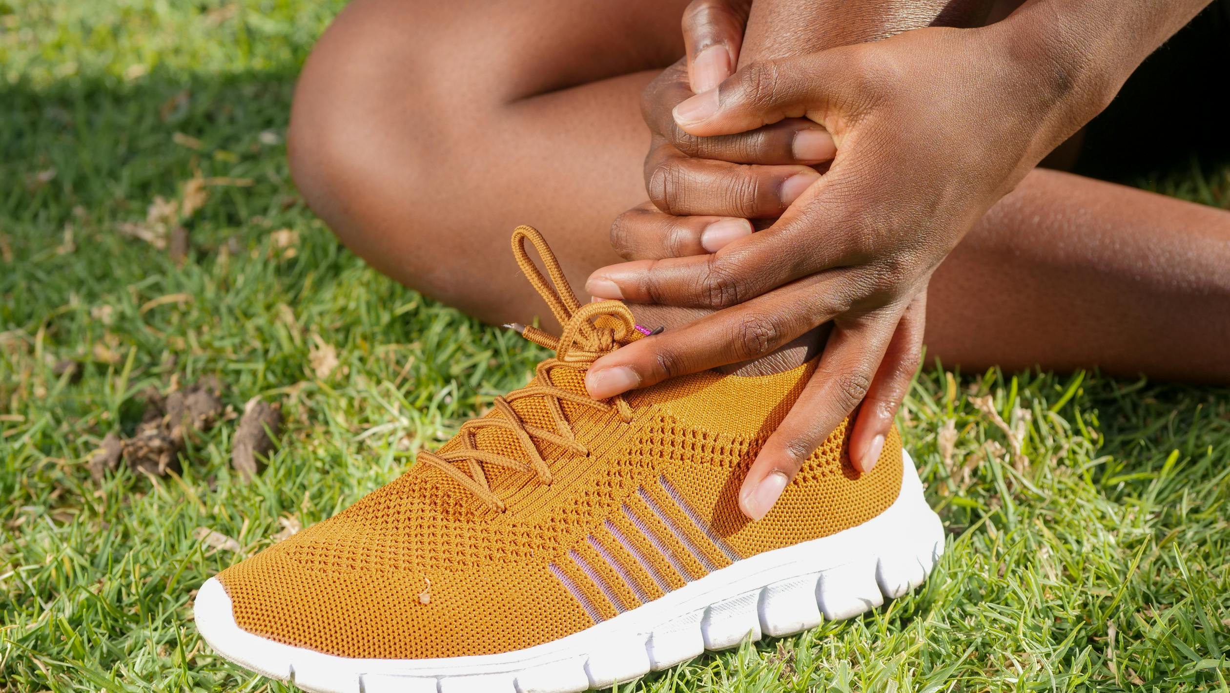 A person holding their foot in pain, indicating possible foot issues.