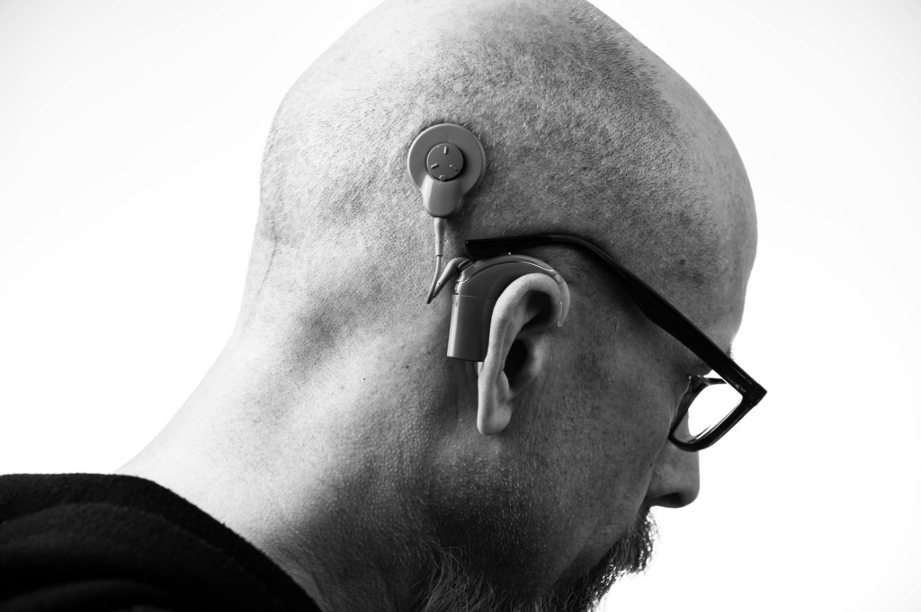 A person wearing a hearing aid to improve their hearing ability.