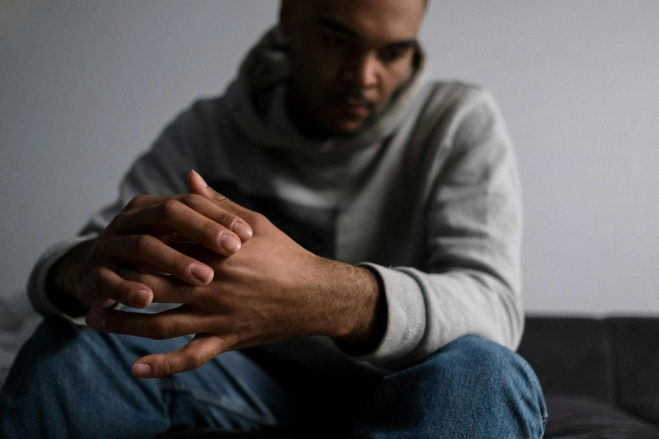 A man looking distressed sits with his hands folded.