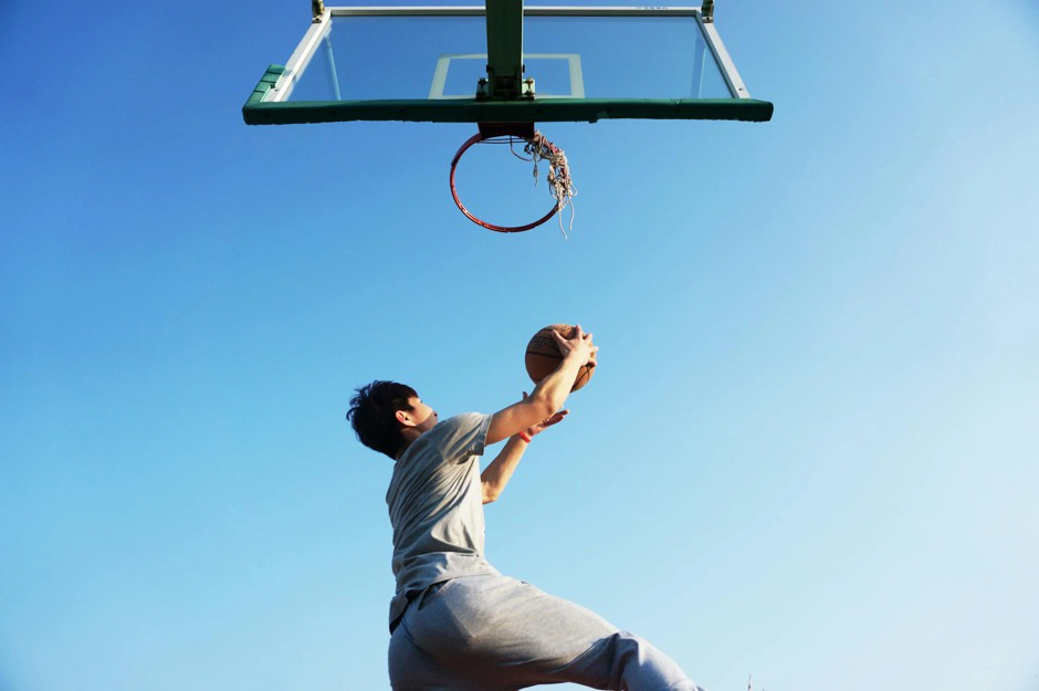 A young athlete laying up a basketball.