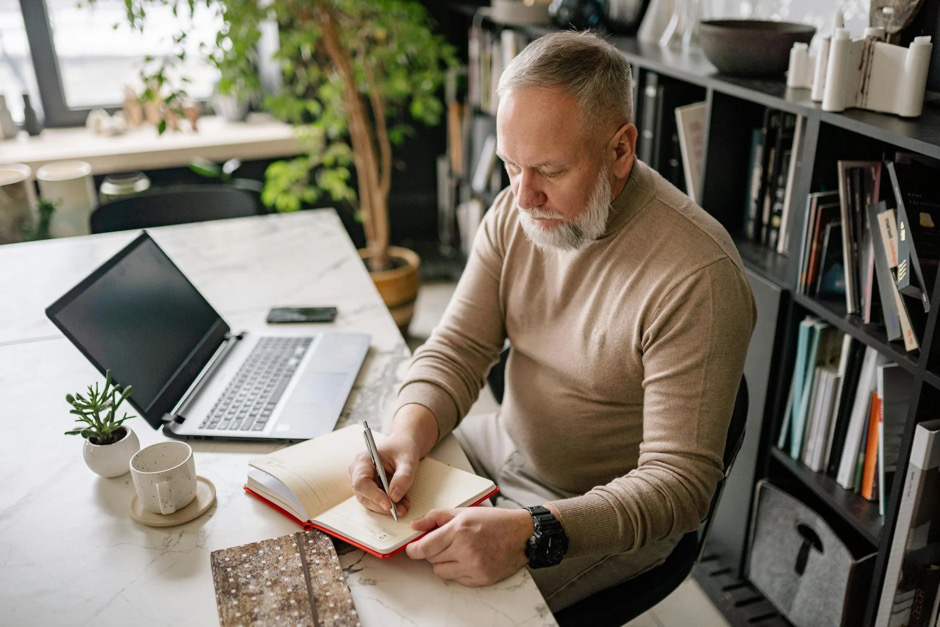 A man writing in a notebook, setting goals for managing joint pain and improving mobility.