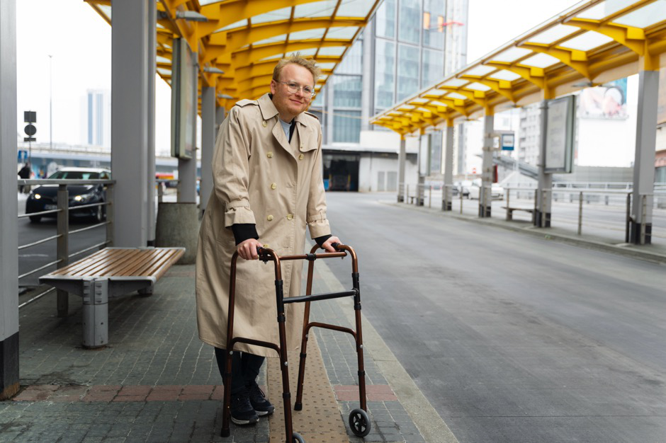 A man using a walker while waiting at a bus stop.