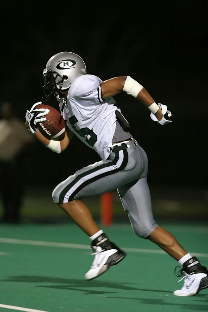 A young football player runs on a football field.